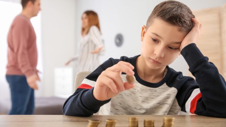 Sad little boy with coins and his quarreling parents