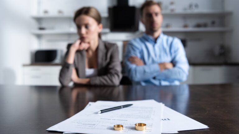 selective focus of couple sitting at table with divorce documents