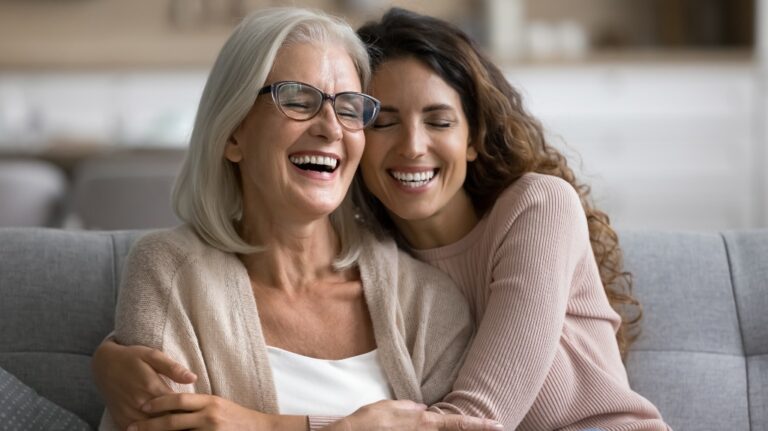 Happy senior mom and adult daughter hugging with their heads touching