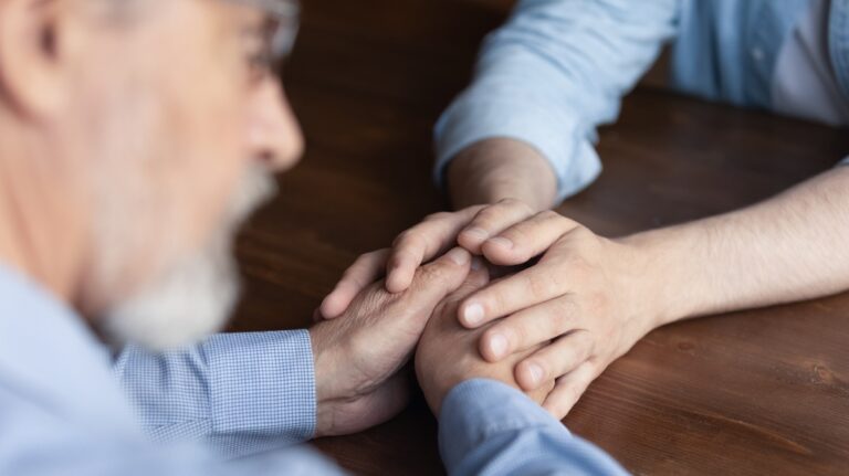 young man holding hands with senior man