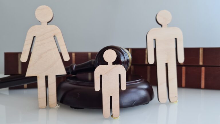 Wooden figures representing a family near a gavel and Law books