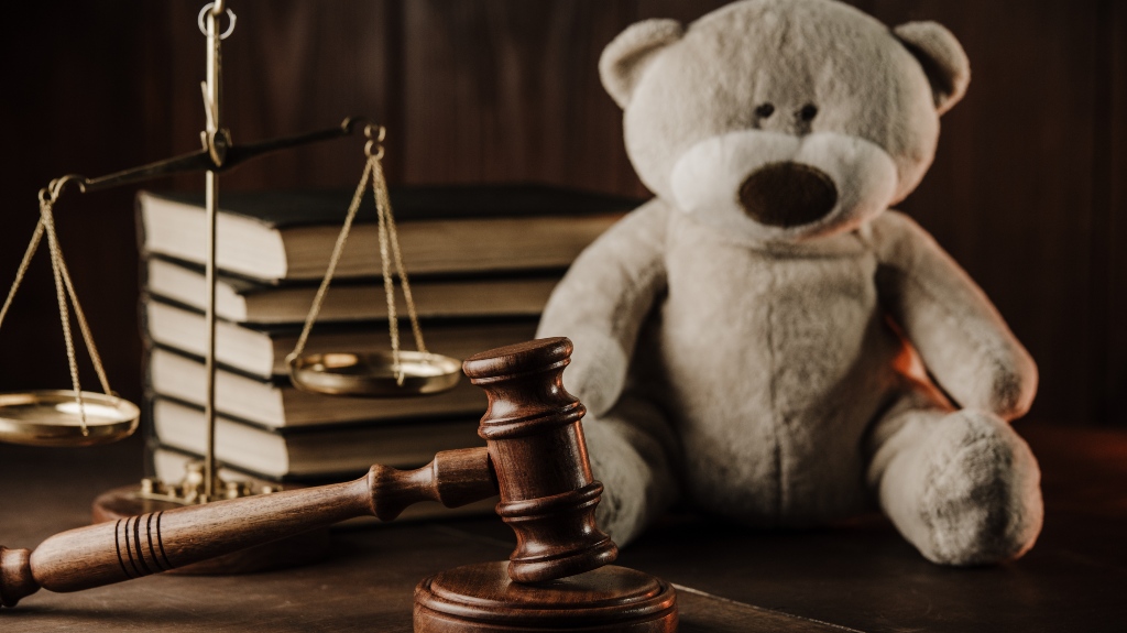 Wooden gavel and teddy bear as symbol of child on a desk