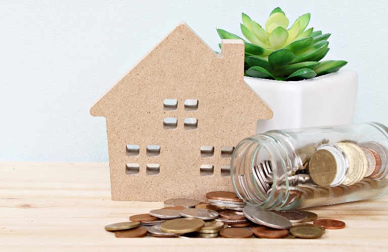 Wooden model of a house and a jar of coins
